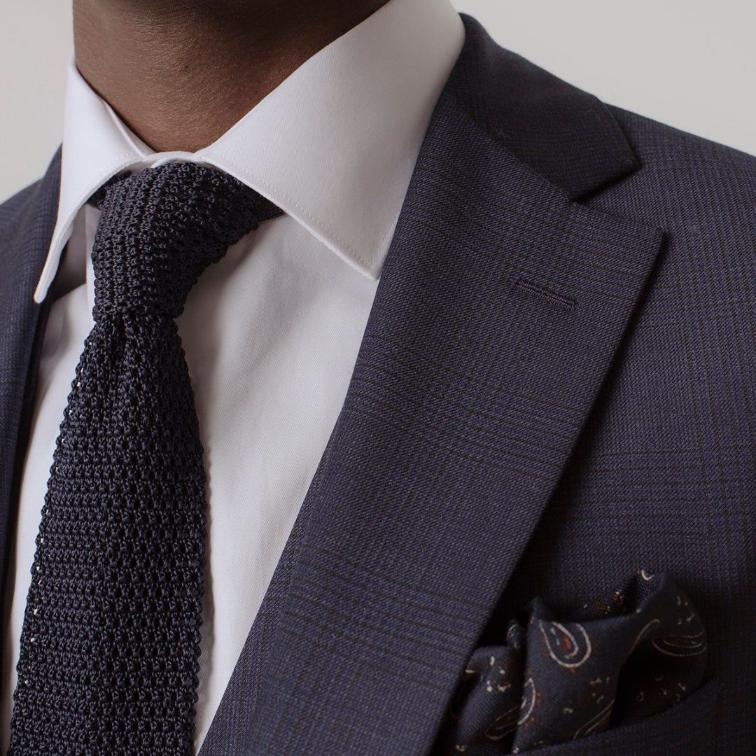 Cravate en maille noir porter avec un costume noir et chemise blanche