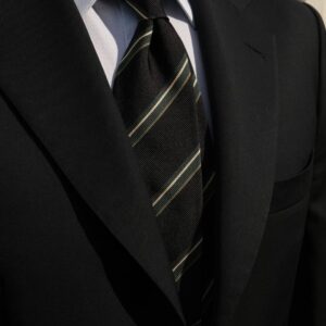 Cravate noir a rayure verte et blaznche porté avec un costume noir et une chemise blanche